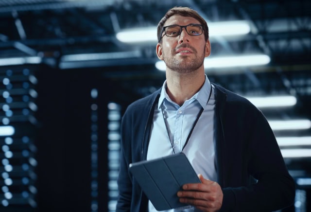 IT specialist walking between rows of hosting servers IT specialist walking between rows of hosting servers